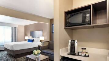 A hotel room with a bed, a desk, a coffee maker, a microwave, and a mini-fridge.