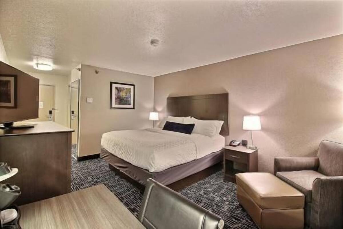 A hotel room with a bed, desk, chair, and a small table.