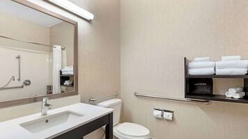 A modern bathroom with a white sink, mirror, and toilet. There are towel racks and a hair dryer shelf.