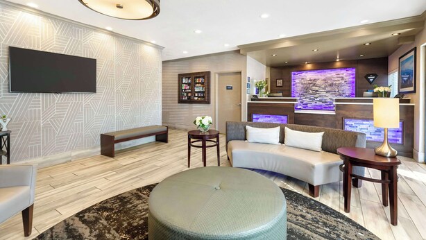 Uma sala de estar moderna com televisão de tela plana, sofá, um banco e um banquinho redondo.