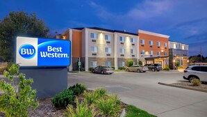 Um hotel Best Western com uma placa, várias vagas de estacionamento e fachada bem iluminada.