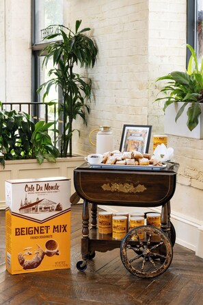 A dining area with a vintage cart, a box of Café Du Monde Beignet Mix, and a framed picture of a café.
