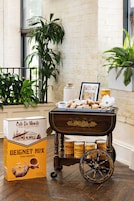 Un coin repas agrémenté d’un chariot d’époque, d’une boîte de préparation pour beignets Café Du Monde et d’un tableau représentant un café.