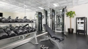 Une salle de sport équipée de matériel de musculation, de bancs et d’un miroir.