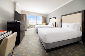 A hotel room with two beds, a desk, a TV, and a view of the city. - The Riverfront Hotel New Orleans (New Orleans)