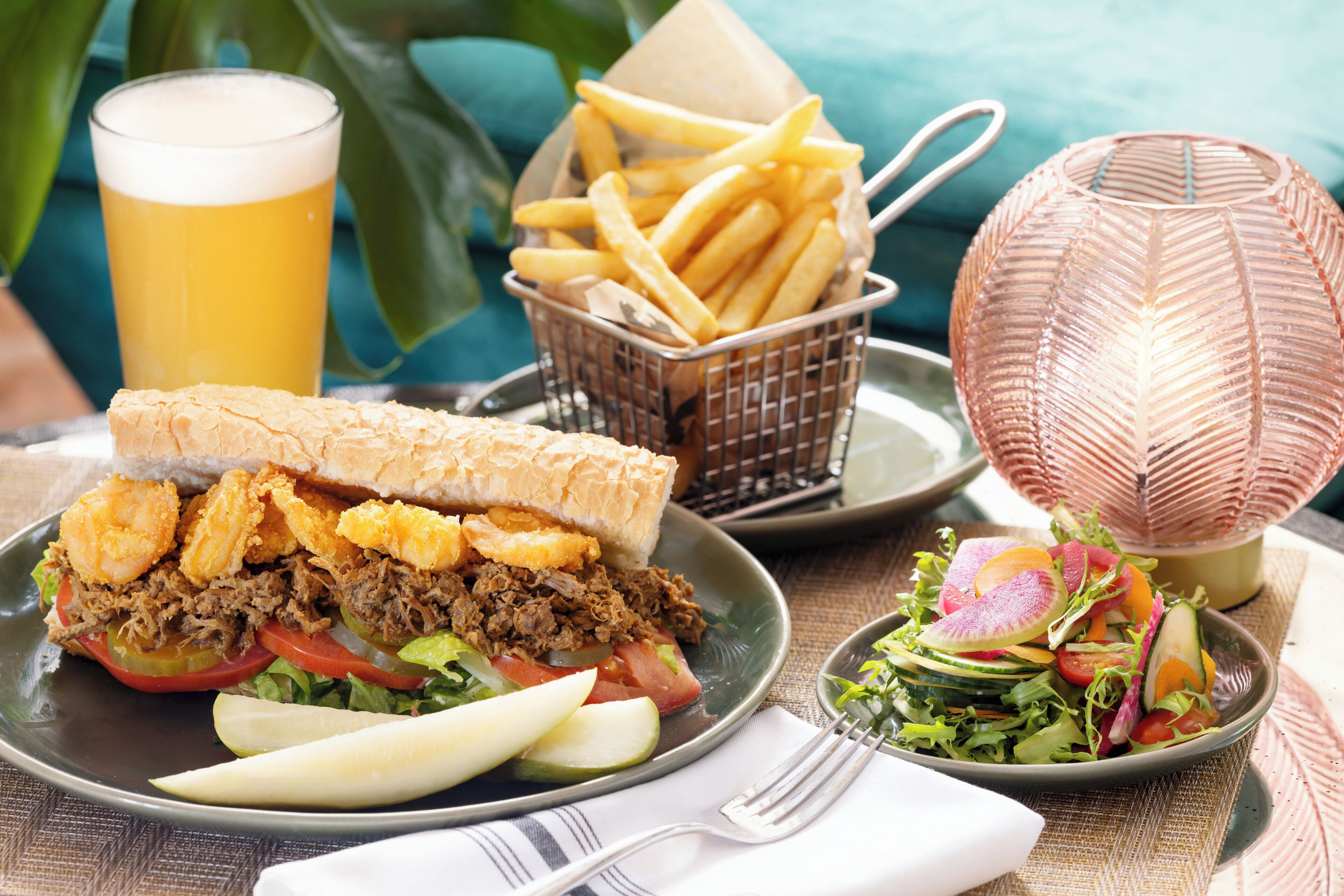 A meal with a sandwich, fries, a salad, and a drink on a table.