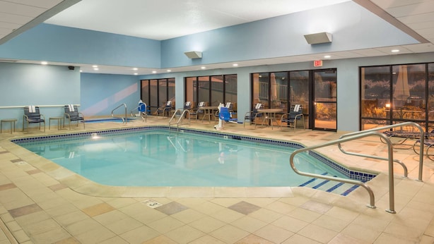 Ein Hallenbad mit klaren Glaswänden, Fliesenboden und blauer Decke.