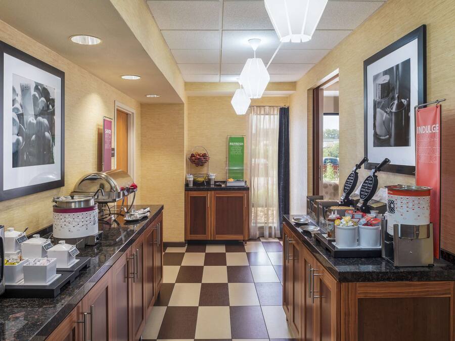 A hotel kitchen with a checkered floor, a coffee station, and a buffet area.