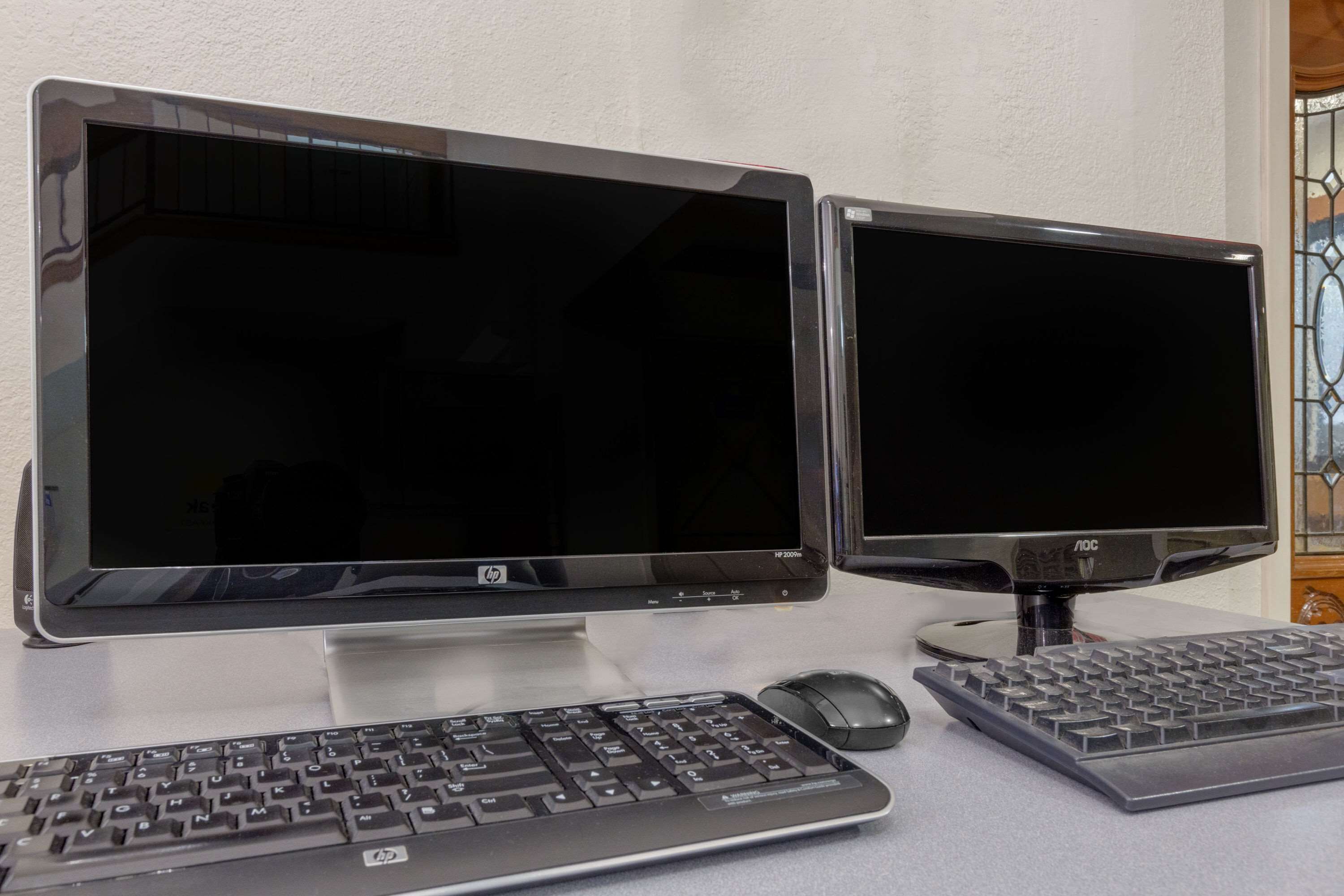 Deux écrans HP sur un bureau, avec un clavier et une souris.