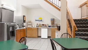 A breakfast area with a Daybreak sign, ice cube machines, a coffee machine, and a refrigerator.