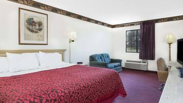 A hotel room with a large bed, a desk, a chair, a television, and a window with curtains.