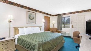 A hotel room with a bed, a desk, a chair, a television, and a window.