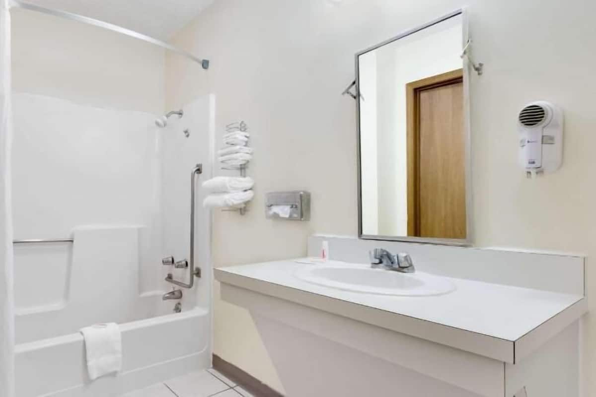 Un baño con bañera, lavabo, espejo y toallero.