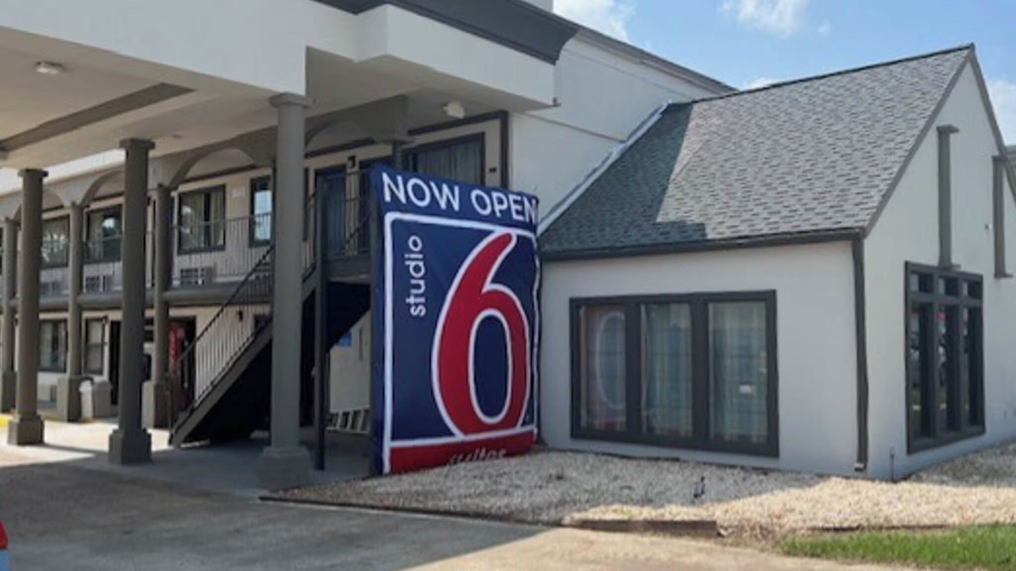Ein Gebäude mit einem gut sichtbaren Schild 'NOW OPEN' für 'studio 6', das auf eine Neueröffnung hinweist.