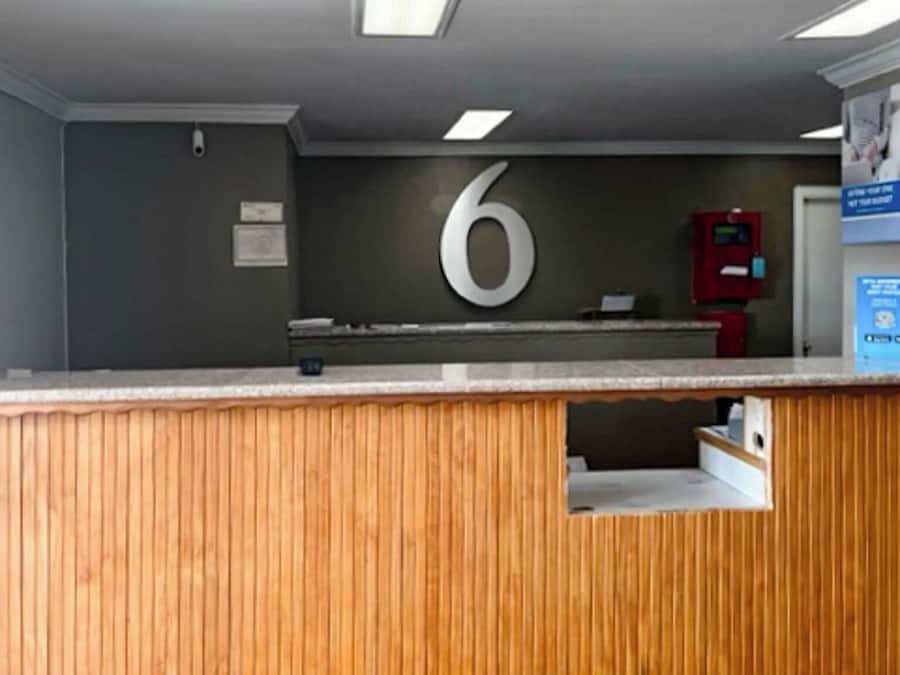 A reception desk with a number '6' sign above it, a fire extinguisher, and a blue informational poster on the wall.