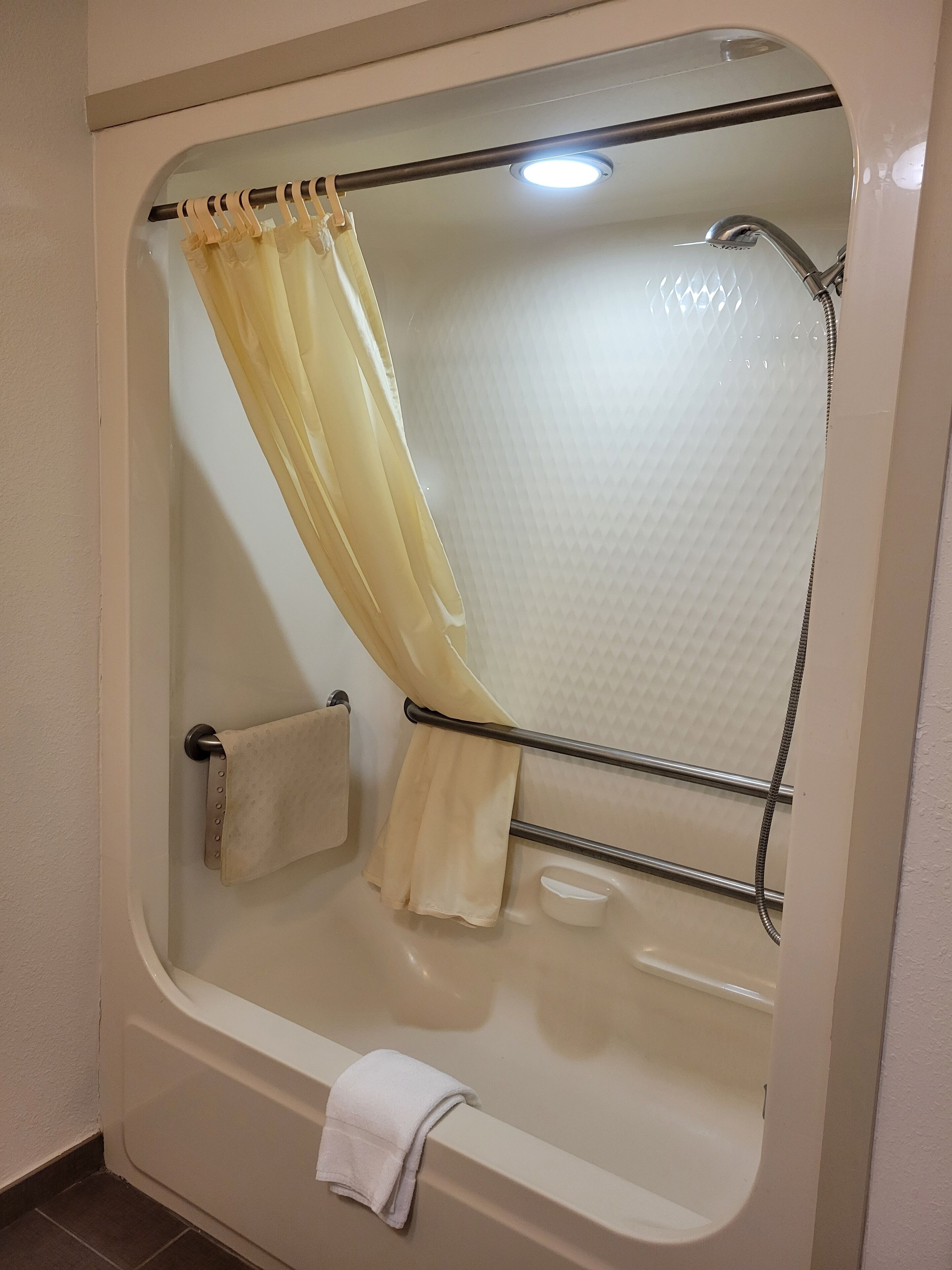 A bathroom with a bathtub, a shower, and a towel rack.