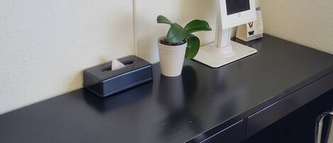 A desk with a tissue box, a potted plant, and a digital kiosk.