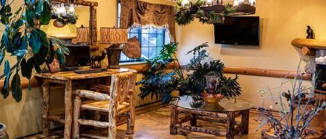 A rustic interior with wooden furniture, a fireplace, and various plants.