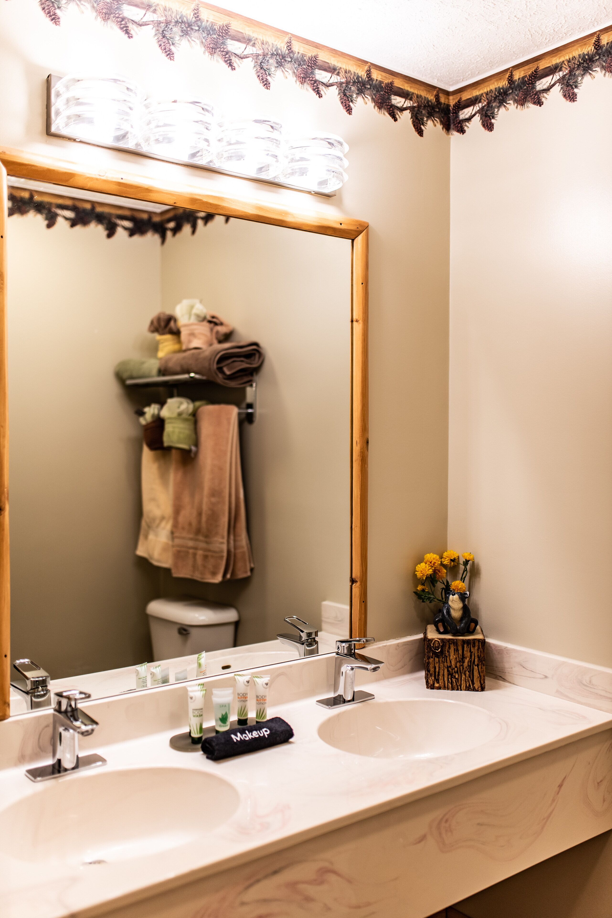 Ein Badezimmer mit einem großen Spiegel, zwei Waschbecken und einem Waschtisch mit Toilettenartikeln.