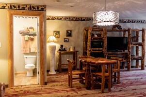 A rustic interior with a wooden dining table, chairs, a television, and a decorative lamp.