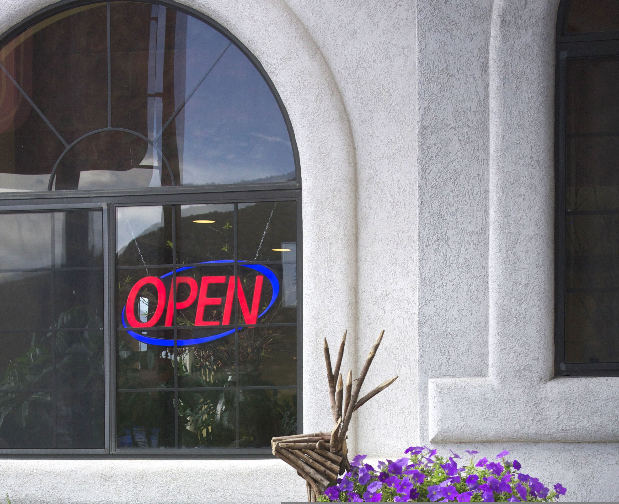 A storefront with a large arched window and a neon 'OPEN' sign.