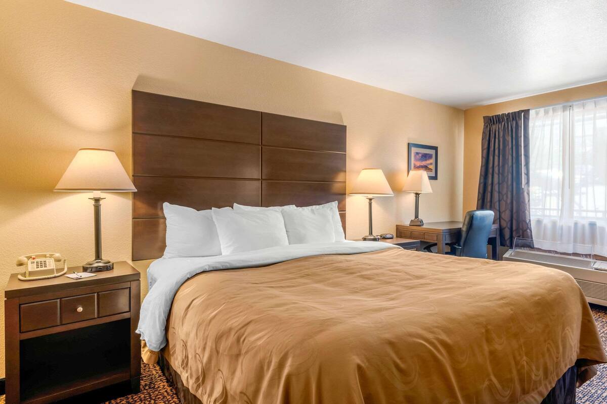 Een hotelkamer met een groot bed, twee bedlampen, een bureau en een stoel.