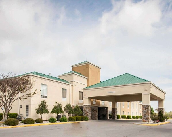 A hotel with a green roof, beige exterior, and a covered entrance.