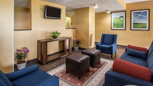A lobby with a reception desk, seating area, and a television mounted on the wall. - Quality Inn Hayti North (Hayti)