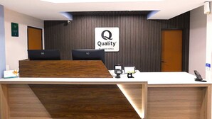 A hotel reception desk with a 'Quality by Choice Hotels' sign, a computer, a phone, and a payment terminal. - Quality Inn Pontiac (Pontiac)