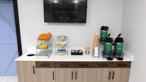 A breakfast bar with a TV above it, and a coffee station with water and coffee dispensers. - Quality Inn Pontiac (Pontiac)