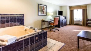 A hotel room with a large bathtub, a desk with a chair, a television, and a window with curtains. - Quality Inn Pontiac (Pontiac)