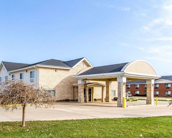 A hotel with a brick facade, a covered entrance, and a parking area.