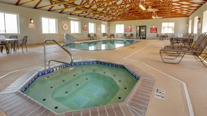 Piscina interior con varias pistas de natación, rodeada de zonas de estar y mesas.