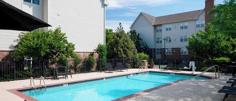 A rectangular swimming pool with a red border, surrounded by a paved deck.