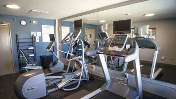 A gym with treadmills, ellipticals, and a mirrored wall.