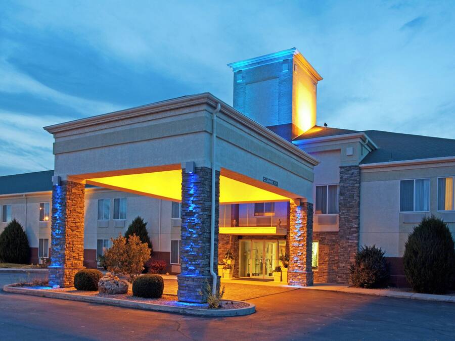 A hotel with a covered entrance, stone pillars, and a clear sky.