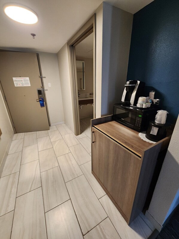 A hotel corridor with a kitchenette area featuring a coffee maker, microwave, and storage cabinets. - Holiday Inn Express La Junta by IHG (La Junta)
