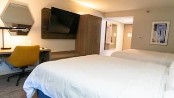 Habitación de hotel con una cama grande, un escritorio con silla, un televisor de pantalla plana y un espejo en la pared.
