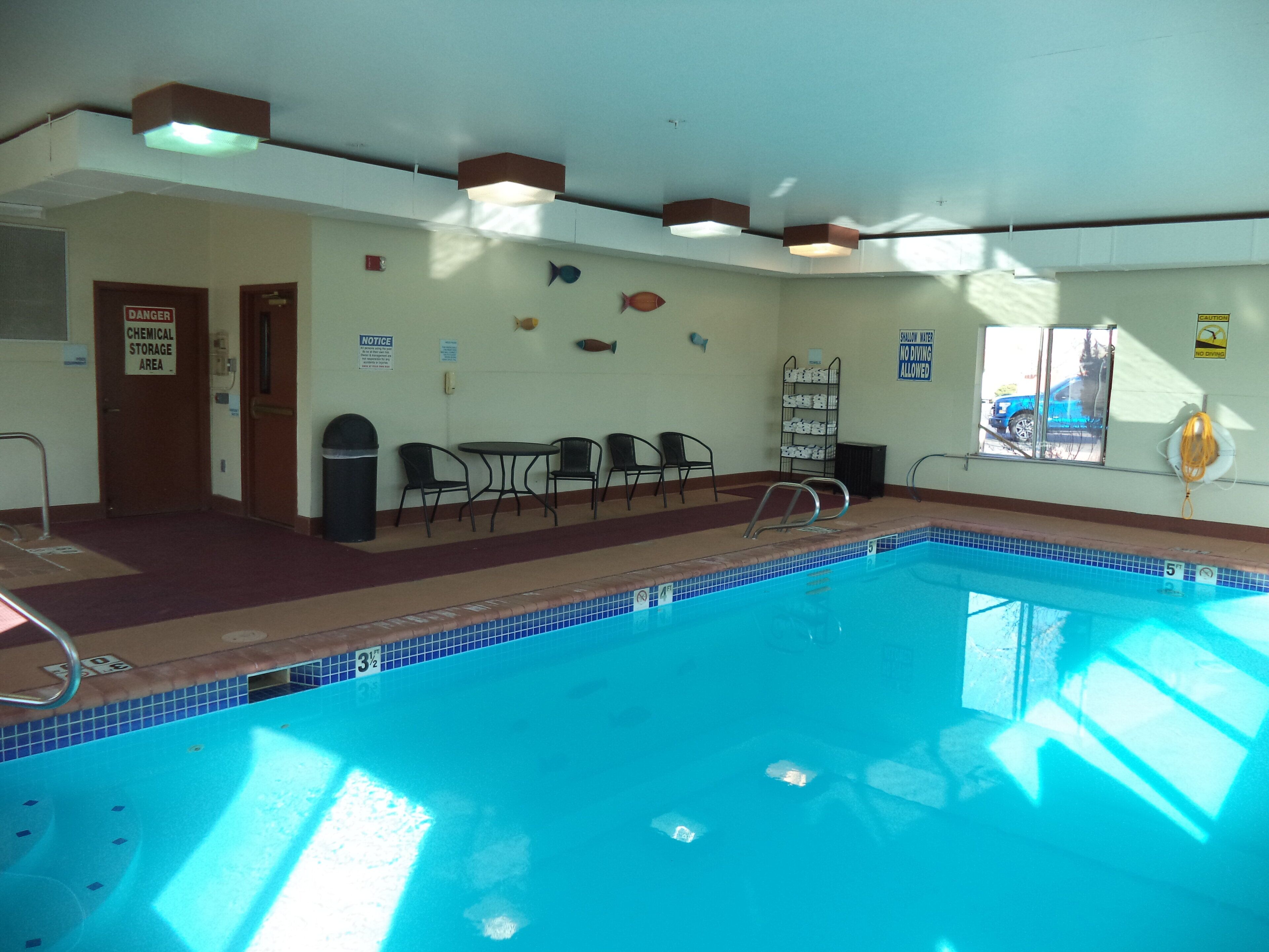 A swimming pool with a tiled edge, a trash can, and a notice sign on the wall.