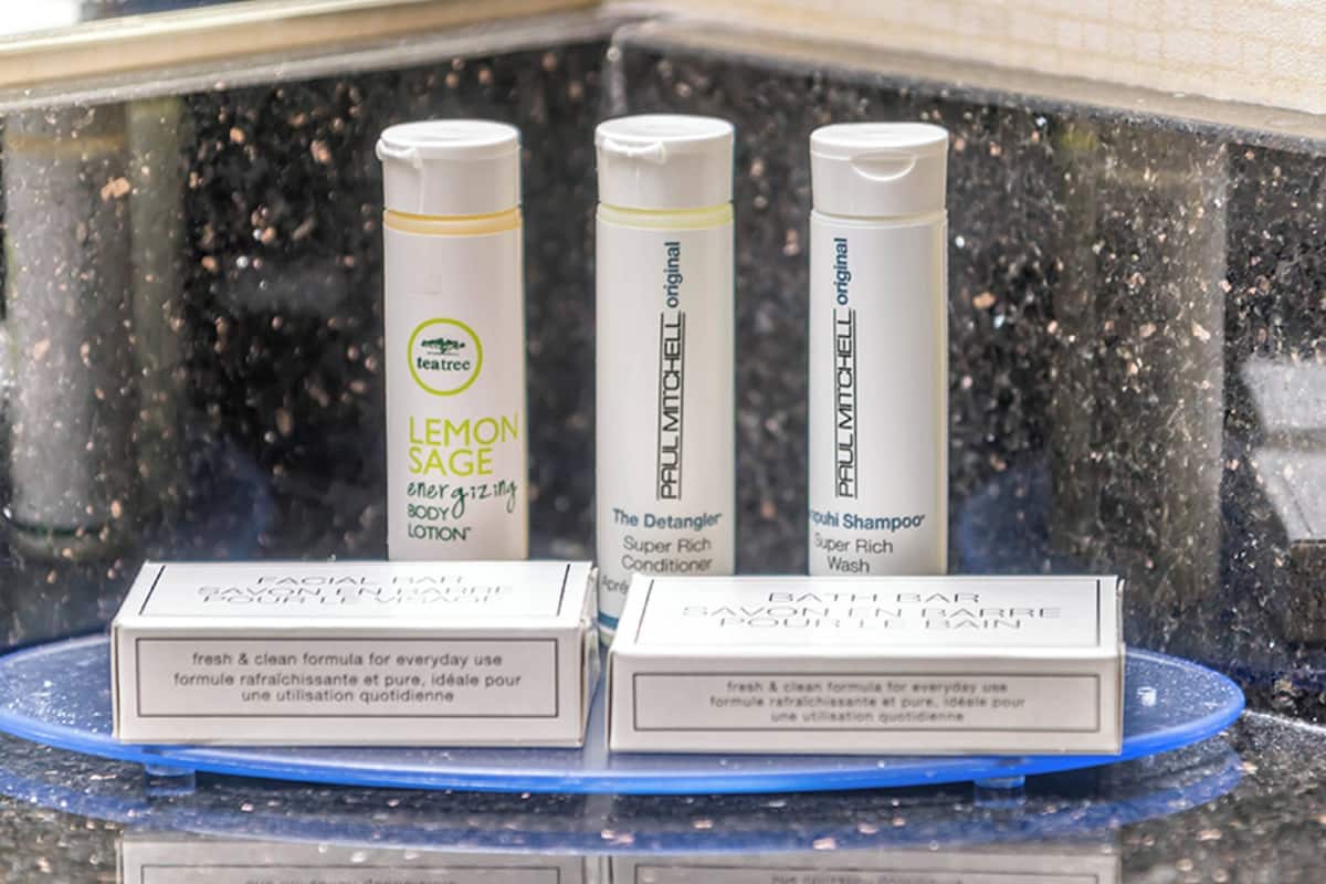 A display of three personal care products: a lemon sage lotion, a Paul Mitchell conditioner, and a Paul Mitchell shampoo.