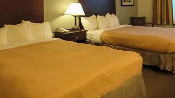 A hotel room with two beds, a nightstand with a lamp, and a framed picture on the wall.