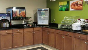 A hotel kitchen with a coffee machine, a water cooler, and a waffle display.