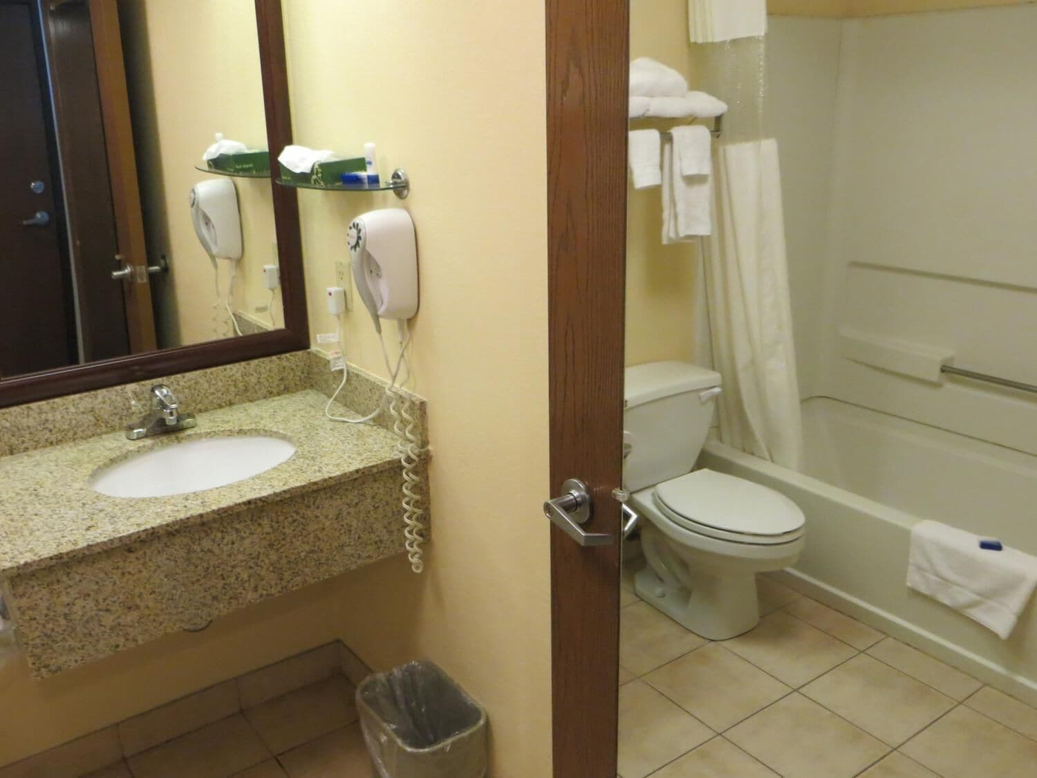 Un baño con lavamanos de granito, inodoro, ducha y espejo.