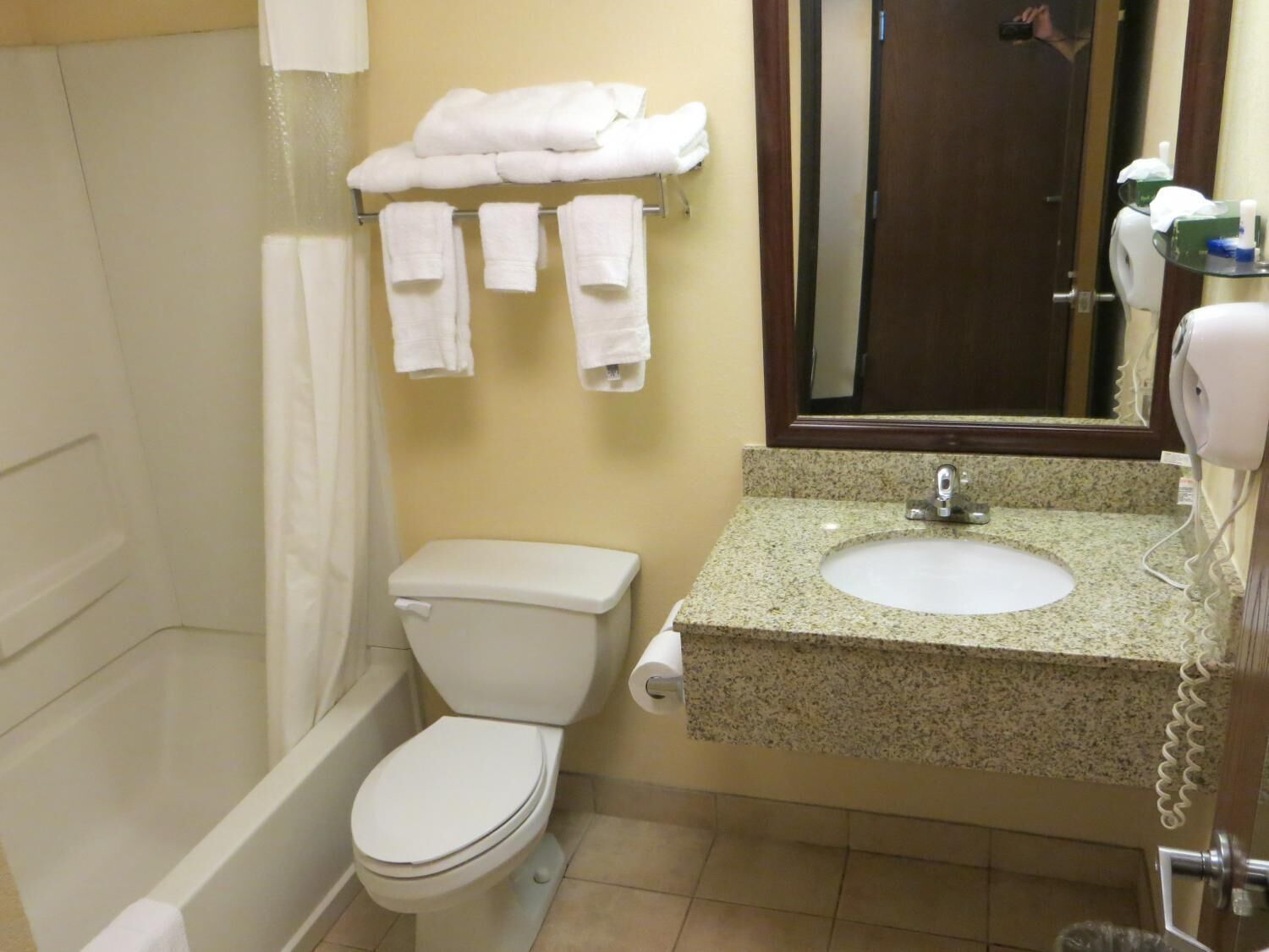 Un baño con inodoro, lavamanos y un perchero con toallas.
