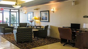 A lobby with patterned chairs, a desk with a computer, a lamp, and framed artwork on the walls.
