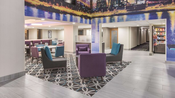Een moderne lobby met zithoeken, een kamerbreed tapijt en een stadsgezichtsmural op de muur.