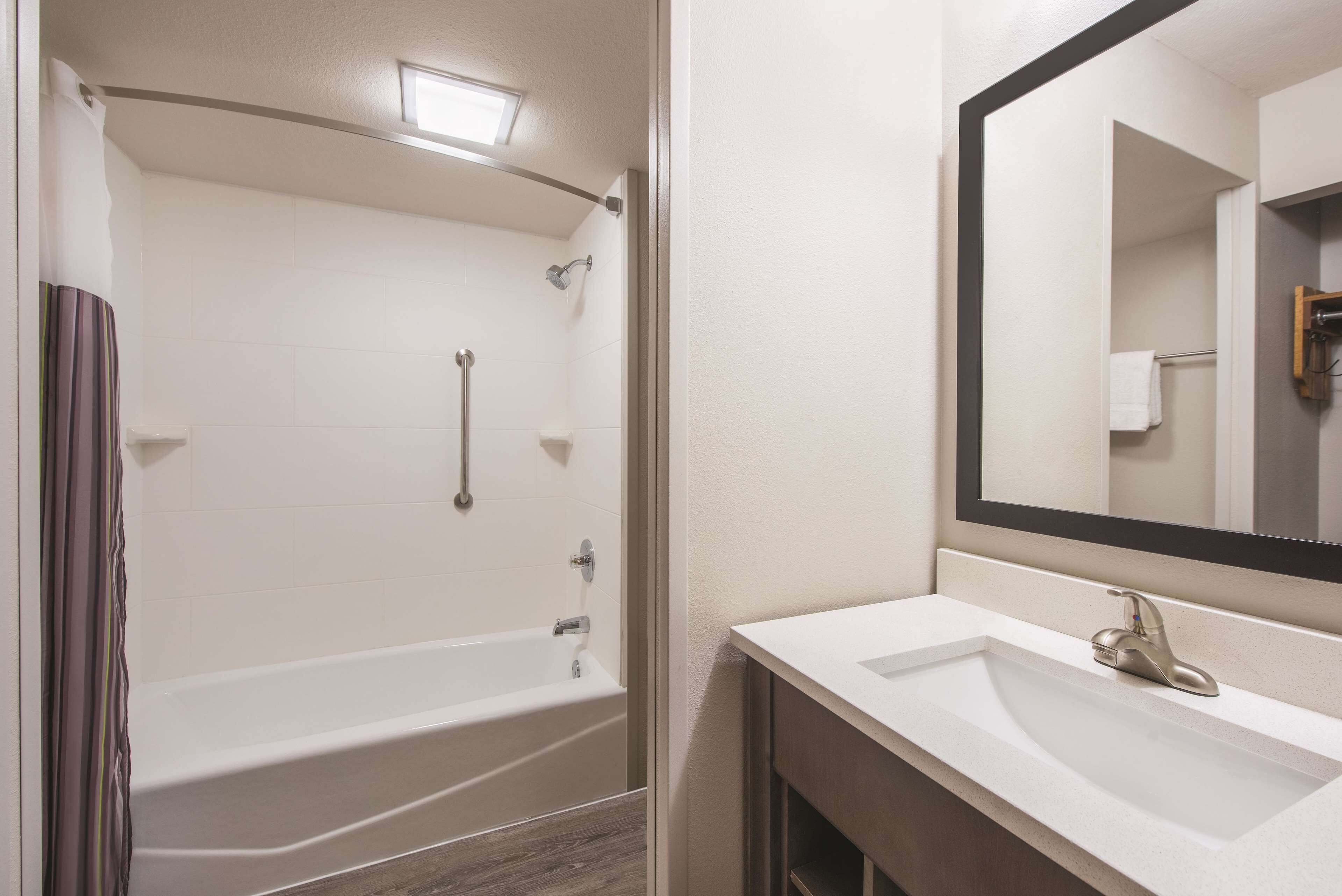 A bathroom with a bathtub, a sink, and a mirror.