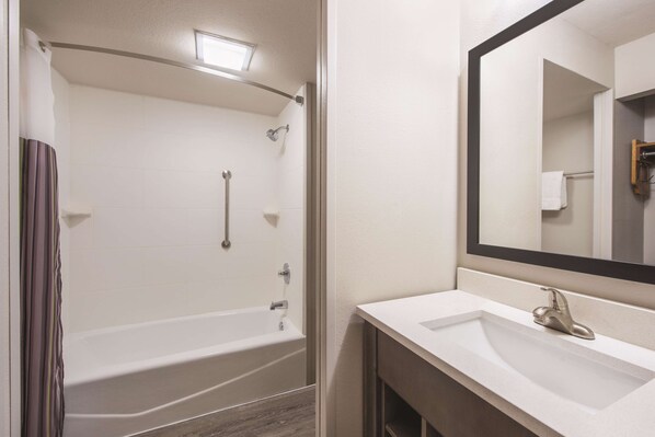 Un baño con bañera, lavabo y espejo.