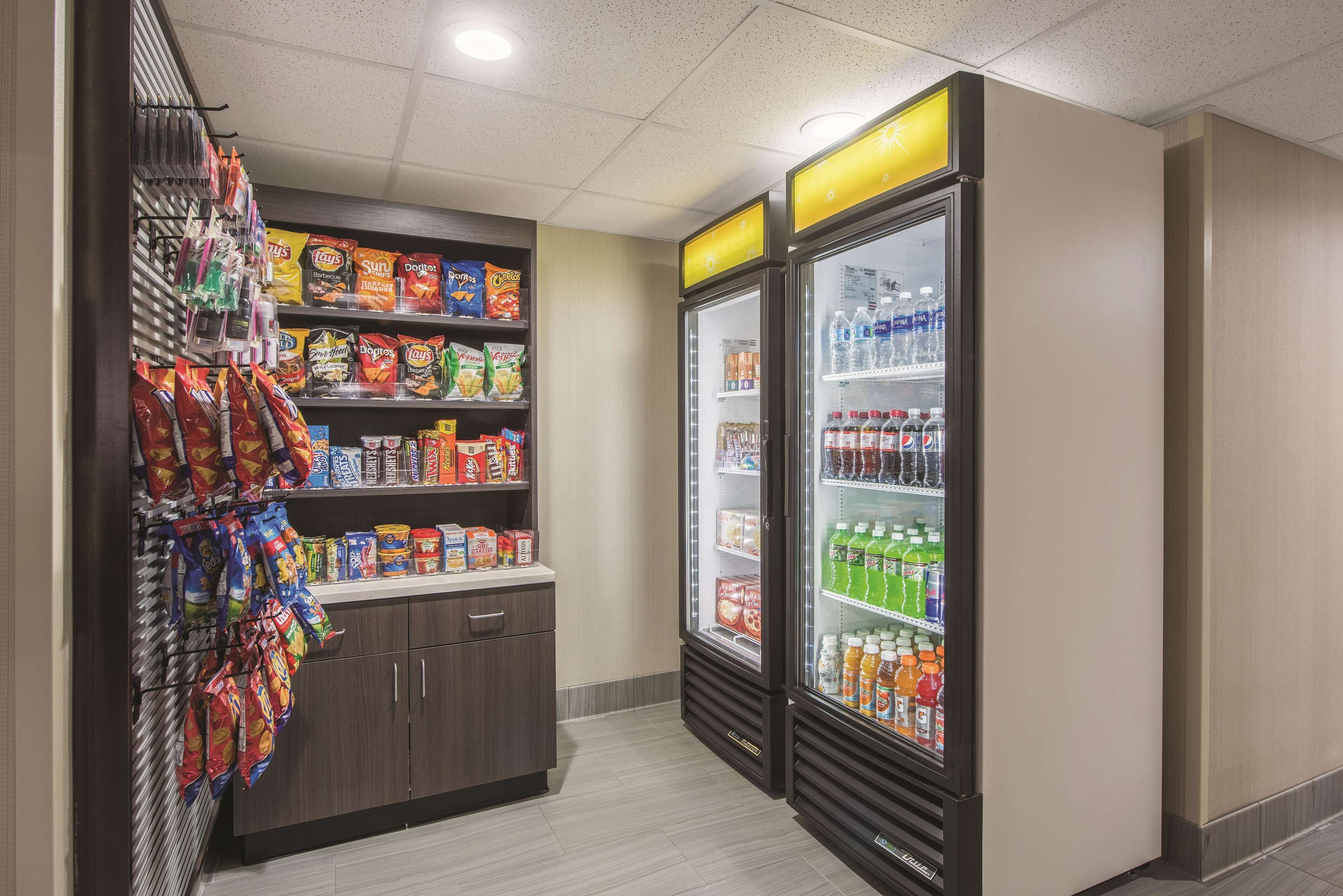 Zona de venta automática con estantes llenos de papas fritas, bocadillos y una variedad de bebidas.