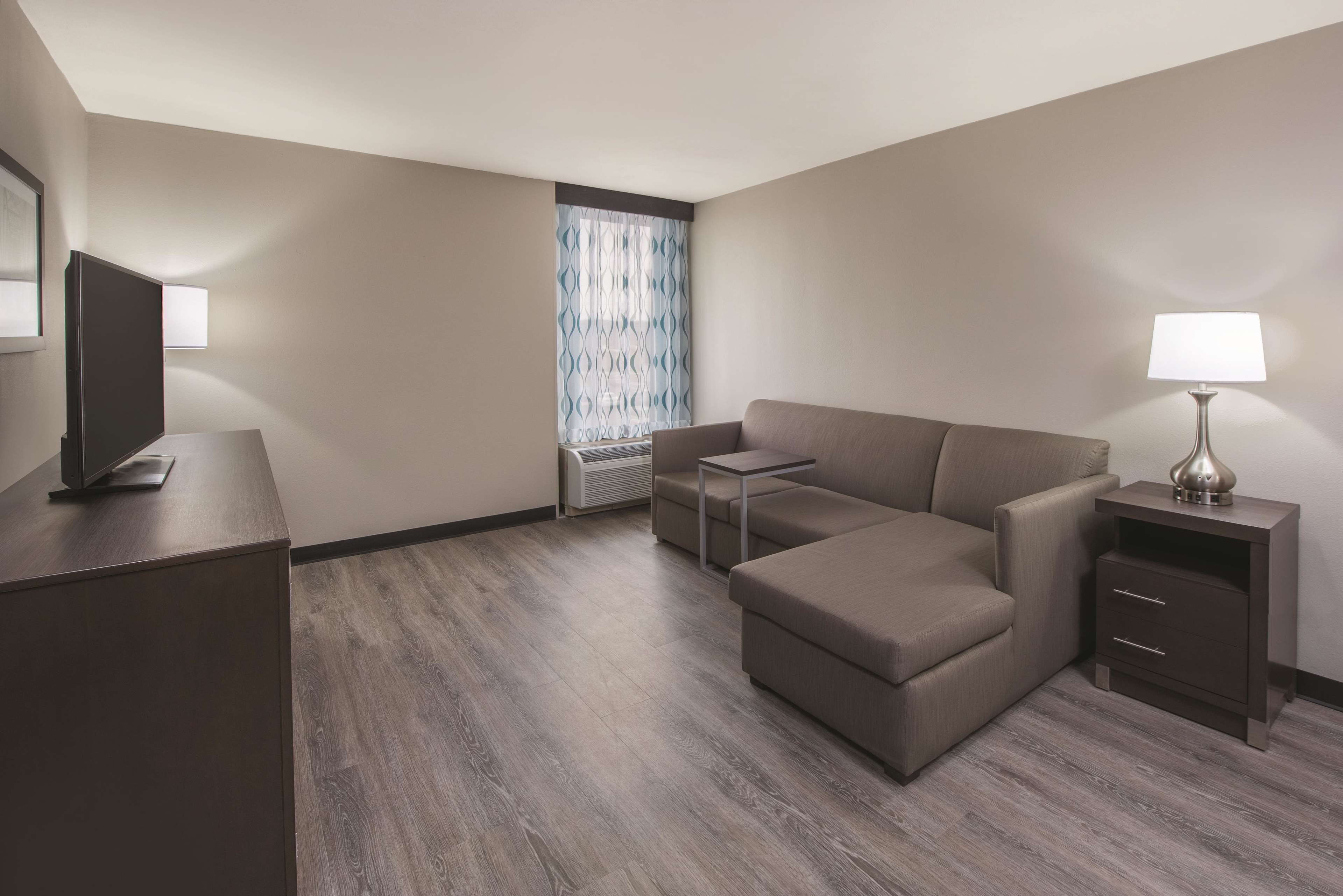 Una habitación de hotel moderna con sofá, una mesita, televisor y lámpara.